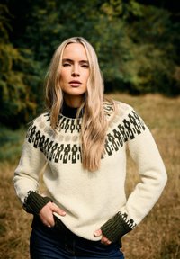 Gestrickter Pullover in Creme mit einem gemusterten schwarzen Schulterbereich, grünen Bündchen und einer lockeren Passform. Verfügt über eine strukturierte Oberfläche und einen runden Ausschnitt.