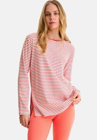 Haut à manches longues rayé rouge et blanc avec une coupe décontractée, un décolleté en scoop et des fentes latérales. Assorti à des leggings corail vif.