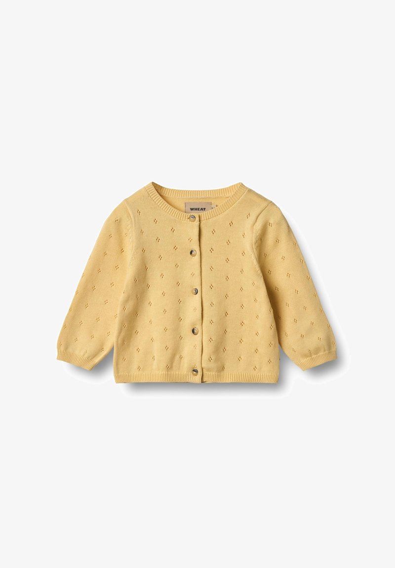 Kollane kudum kardigan, millel on ümmargune kaelus, pikad varrukad, nööpide kinnitamine ja väikesed dekoratiivsed augud kogu kangas.