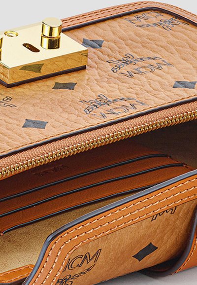 Brun læderpunge med gyldent spænde, synlig lynlås og sorte logo mønstre, der viser åbne kortlommer og indvendige rum.