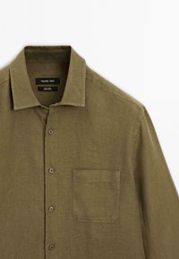 Olive green linen shirt with a front pocket, button-down collar, and five buttons down the placket. Textured fabric, casual design.