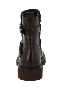 Stivale alla caviglia in pelle marrone con punta rotonda, zip laterale, due cinturini regolabili con fibbia e suola in gomma texturizzata.