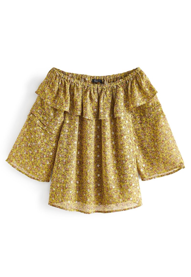 Blouse jaune à fleurs, dénudée des épaules, avec un col volanté et de larges manches courtes. Tissu léger avec un motif texturé.