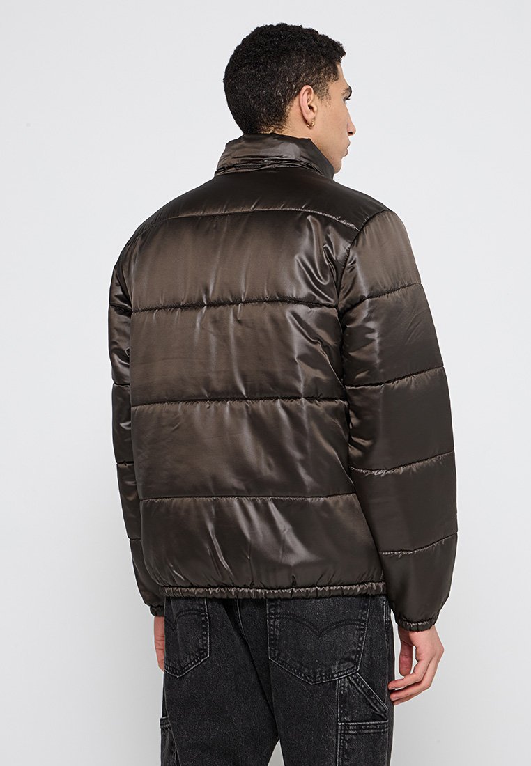 Giacca a vento marrone, trapuntata, con colletto alto, finitura satinata liscia, orlo e maniche elastiche, vista da dietro.