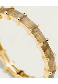 Bague en ton or ornée de pierres translucides rectangulaires aux teintes terreuses, intégrées dans un design géométrique avec des accents texturés.