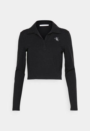 Black cropped long-sleeve polo shirt with a collar. Features a small embroidered logo on the left chest. Soft, stretchy fabric.
