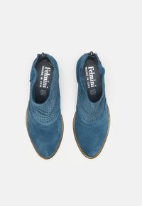 Chaussures en suédine bleue avec des détails perforés, bout arrondi et fermeture éclair sur le côté. Elles présentent une semelle contrastante avec des accents de couture.