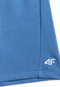 Tissu bleu à texture côtelée, avec un logo blanc "4F" près de l'ourlet inférieur et des coutures visibles.