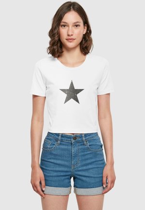 White cropped t-shirt featuring a dark gray star graphic on the front. Finished with short sleeves, paired with blue denim shorts.