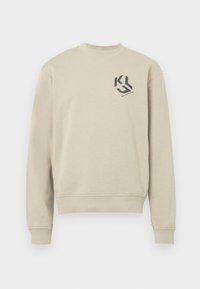 Beige színű, hosszú ujjú pulóver. Kerek nyakkivágással és egy kis fekete logóval a mellkasán. Puha pamut anyag.