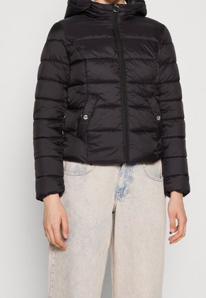 Black quilted puffer jacket with zipper front, snap-button pockets, and hood, worn with light-colored jeans.