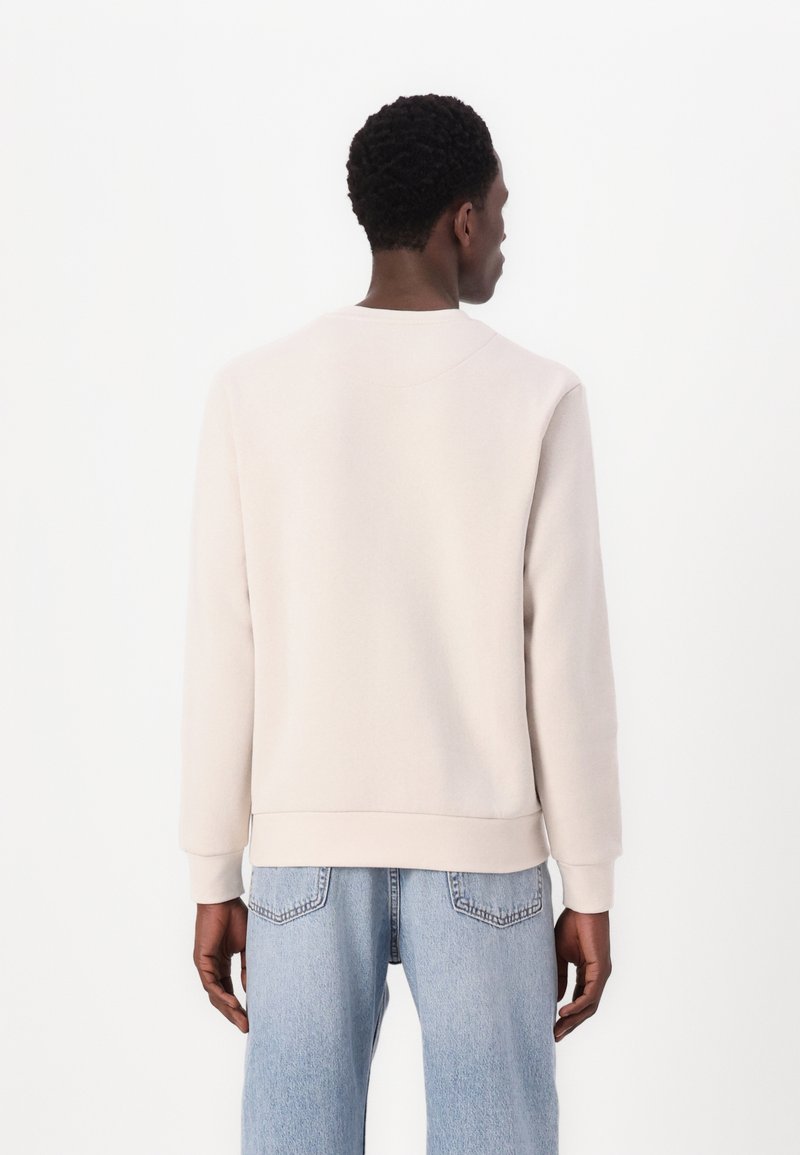 Lichtbeige sweatshirt met lange mouwen, ronde hals en ribgebreide zoom, gecombineerd met lichtblauwe denim jeans. Glad materiaal, casual ontwerp.