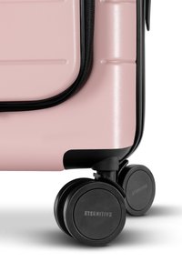 Hartschalentrolley in mattem Pink mit schwarzen Akzenten, verfügt über eine strukturierte Oberfläche, zwei leise Rollen und einen kontrastierenden Reißverschluss.