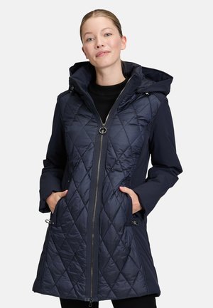 Giacca imbottita trapuntata blu navy con cappuccio, chiusura a zip e tasche laterali, con un tessuto liscio e un motivo a diamante nell'area del petto.