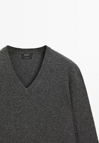 Gray V-neck sweater made of soft fabric, featuring a textured surface and a label on the interior neck. Simple, classic design.