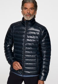 Laivaston sininen puhallettava takki, jossa on tikattu muotoilu, korkea kaulus ja etuvetoketju. Ominaisena hienovarainen logo ja sileä, kiiltävä pinta.