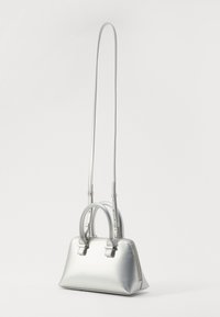 Sac à main métallique argenté avec double poignée et une bandoulière longue amovible, présentant une texture lisse et un design minimaliste.