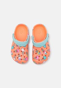 Crocs naranjas con un patrón de conos de helado coloridos. Cuenta con una correa azul claro y agujeros de ventilación para mayor transpirabilidad.