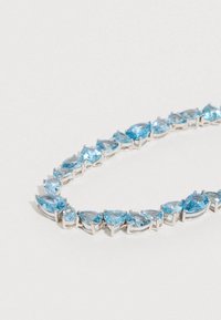 Pulsera de tono plateado con múltiples gemas azules en forma de pera, dispuestas secuencialmente, con una superficie pulida y un engaste brillante.