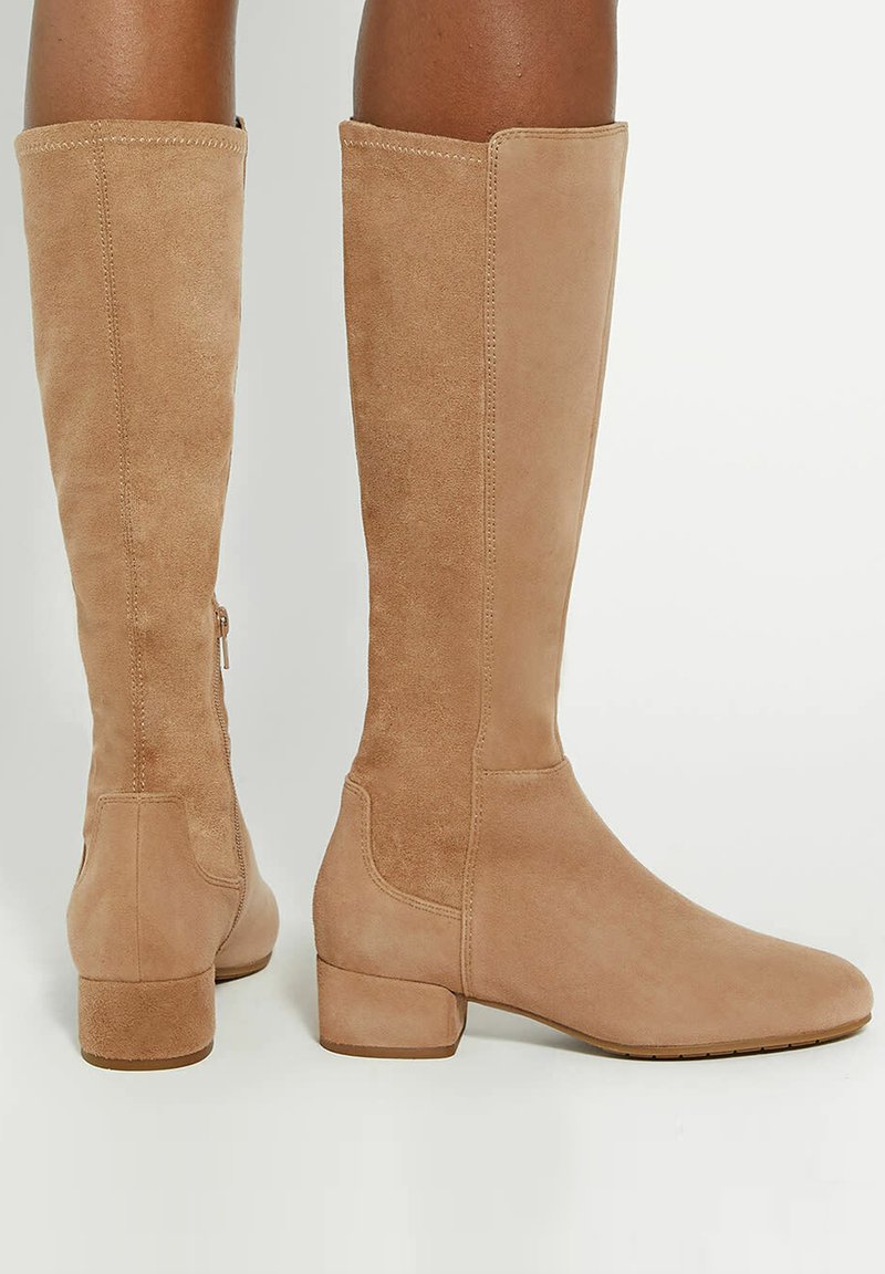 Tan suède kniehoge laarzen met een afgeronde neus en lage blokhak; heeft een gladde afwerking en minimalistisch ontwerp. Verstelbare ritsdetails.