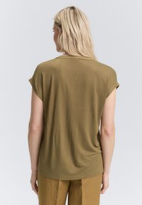 T-shirt en tissu doux de couleur vert olive, à manches courtes et coupe décontractée, avec un encolure arrondie et une texture lisse. Vue arrière présentée.
