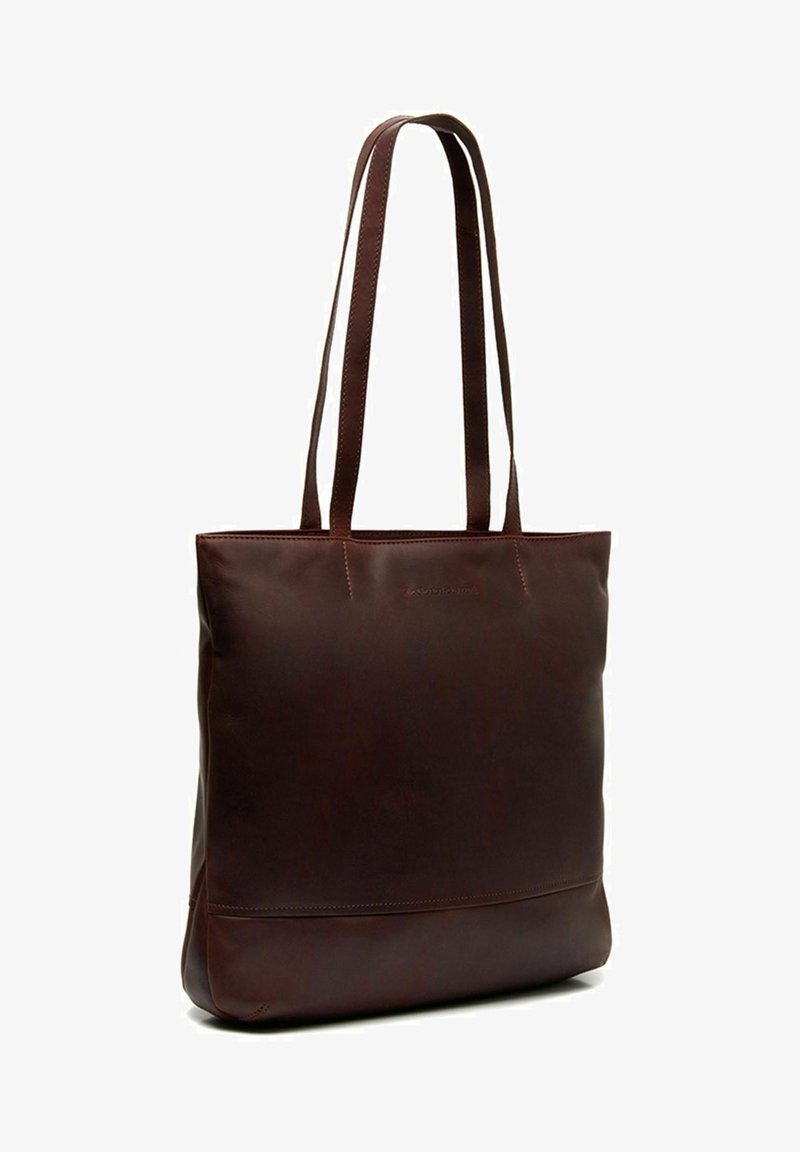 Sac fourre-tout en cuir marron avec de longues sangles, forme rectangulaire, texture lisse et un design minimaliste mettant en avant un logo discret à l'avant.