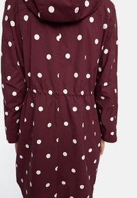 Burgundowy płaszcz z kapturem, z dużymi białymi kropkami. Zaprojektowany z elastycznym pasem i długimi rękawami dla luźnego kroju.