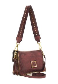Borsa a tracolla in pelle color bordeaux con borchie dorate lungo i bordi, tracolla regolabile e logo decorativo quadrato sul davanti. Superficie texturizzata.