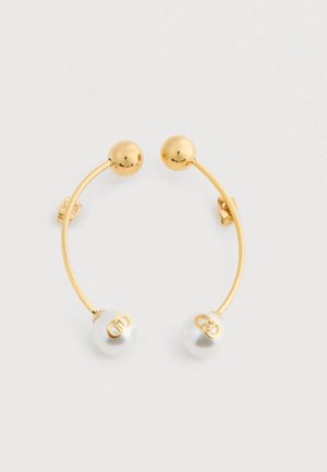 Korvakorut, joissa on kultasävyinen kaareva tanko, toisessa päässä kultapallo ja toisessa päässä valkoinen helmi, jonka koristeena on kultalogo.