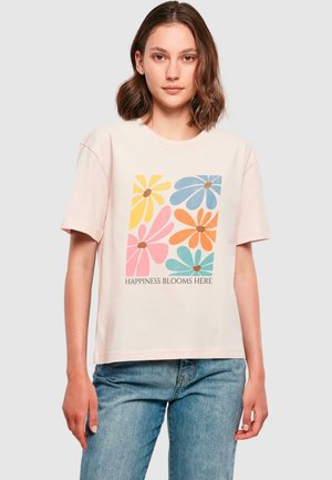 Helle rosa Baumwoll-T-Shirt mit einem floralen Design, das gelbe, rosa, blaue und orangefarbene Blumen zeigt. Darunter steht "HAPPINESS BLOOMS HERE."