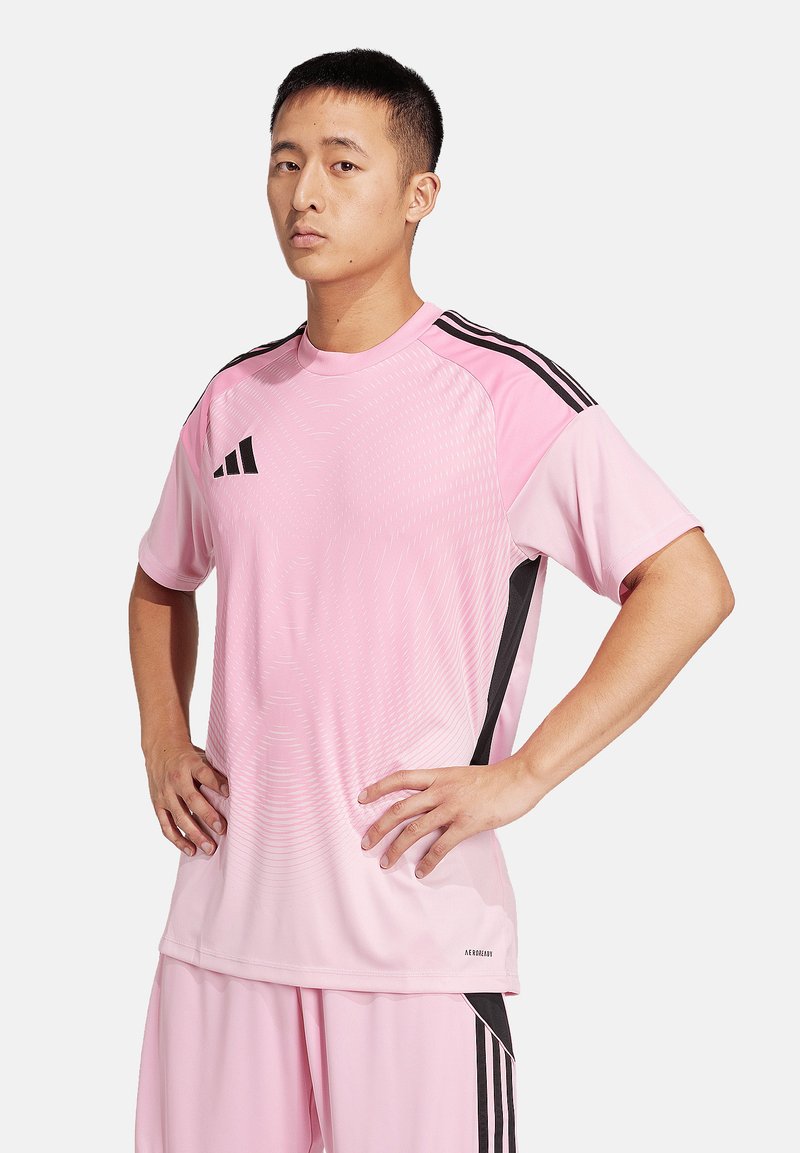Rosa Sportshirt mit schwarzen Seitenstreifen und einem Adidas-Logo. Verfügt über einen Rundhalsausschnitt und eine strukturierte Musterung auf dem Stoff.