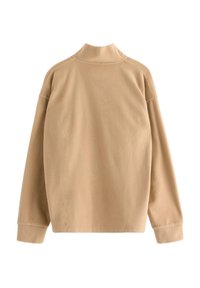 Vaaleanruskea fleece-huppari, jossa on korkea kaulus, laskeutuvat olkapäät ja pitkät hihat. Pehmeä tekstuuri, jossa on minimalistinen muotoilu eikä näkyviä saumoja.