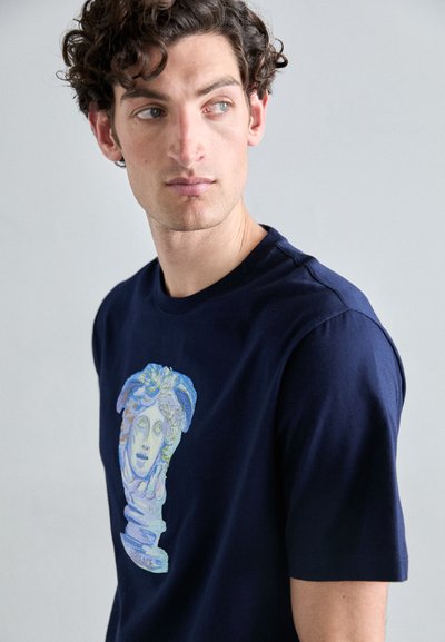 T-shirt en coton bleu marine arborant un graphique coloré d'un buste classique sur le devant, avec des manches courtes et un col rond.