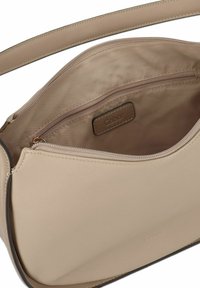 Sac �à main en cuir beige avec une texture lisse, bandoulière ajustable, fermeture éclair, poche intérieure et étiquette de marque.