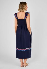 Abito maxi blu navy con corpetto arricciato, spalline arricciate con accenti rosa e blu, e un motivo ondulato multicolore vicino all'orlo.