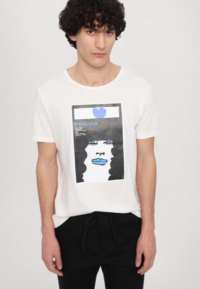 White cotton t-shirt featuring a graphic print of a face with black hair and blue lips, framed by a black and blue design.