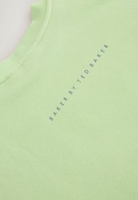 Lysegrøn bomuld T-shirt med rund hals, med trykt tekst "BAKER BY TED BAKER" i en mørkere blå skrifttype. Glat tekstur.