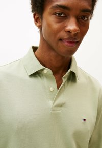 Polo de color verde claro con una tela texturada, con un collar clásico, una tapeta de dos botones y un pequeño logo bordado en el pecho.