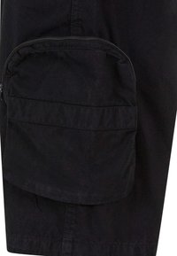 Shorts cargo noirs avec une poche zippée sur le côté, fabriqués en tissu résistant, avec une texture lisse et un design simple.