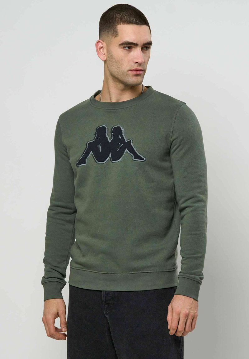 Sweat-shirt vert en coton, avec col rond et manches longues. Orné d'un motif graphique noir sur la poitrine.