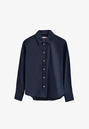 Granatowa koszula na długi rękaw zapinana na guziki, wykonana z gładkiej tkaniny. Posiada szpiczasty kołnierzyk, listwę z guzikami oraz małe czerwone logo na piersi.