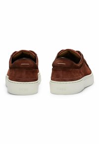 Suede brown slip-on shoes with white rubber soles. Features a padded collar and minimalistic branding on the heel.