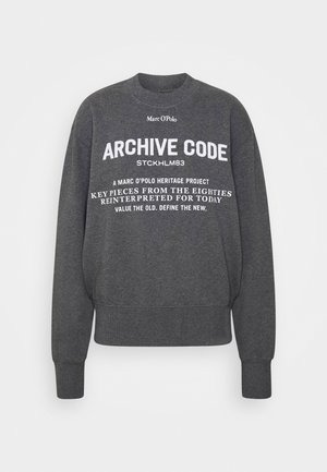 Felpa girocollo grigio scuro con testo bianco: "Marc O’Polo", "ARCHIVE CODE STCKHLM83" e frasi del progetto heritage in caratteri misti.