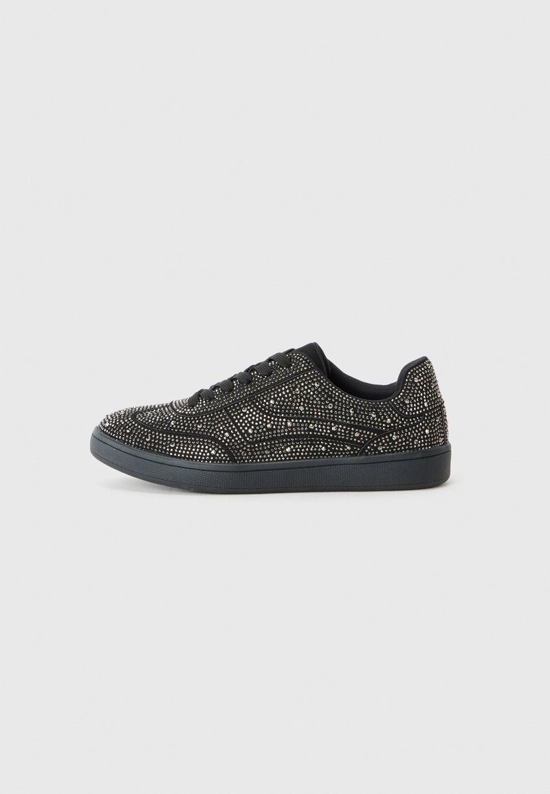 Mustad mustad sneakers, mis on kaunistatud säravate studidega, madala lõikega kujundusega ja nööpidega kinnitamisega, lihtsal valgel taustal.