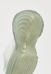 Sneaker sole featuring translucent rubber, wavy design, light green color, textured surface, and visible branding details embossed on the heel.
