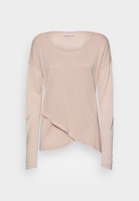 Light pink long-sleeve top with a rounded neckline. Features an asymmetrical hem and soft, textured knit fabric. Casual and relaxed fit.