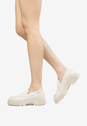 White patent leather loafers with a chunky, ridged sole and a decorative strap across the front, showing smooth texture and minimalistic design.