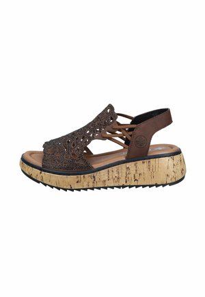 Brown wedge sandal with patterned cut-out upper, elastic side straps, and cork-textured sole with black tread.