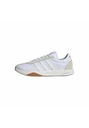Weißer Adidas Sneaker in niedriger Ausführung mit drei weißen Streifen, beigen Velours-Details an Zehen- und Fersenbereich und einer weißen Sohle mit Gummiprofil.