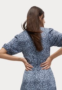 Blå blommönstrad klänning med korta ärmar och insydd midja, med en lätt tygstruktur och en avslappnad design.